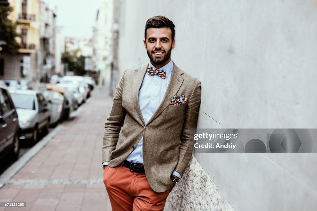 Portrait of young handsome fashion blogger leaned on the wall.