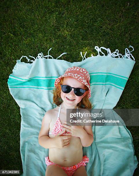 a girl laying on a towel on the grass - girls sunbathing fotografías e imágenes de stock