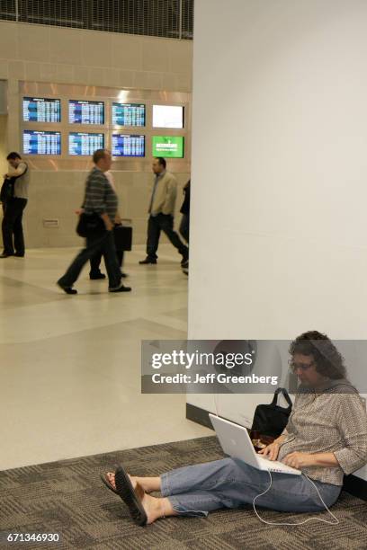 Woman sitting on the floor using her laptop at Detroit Metropolitan Wayne County Airport.