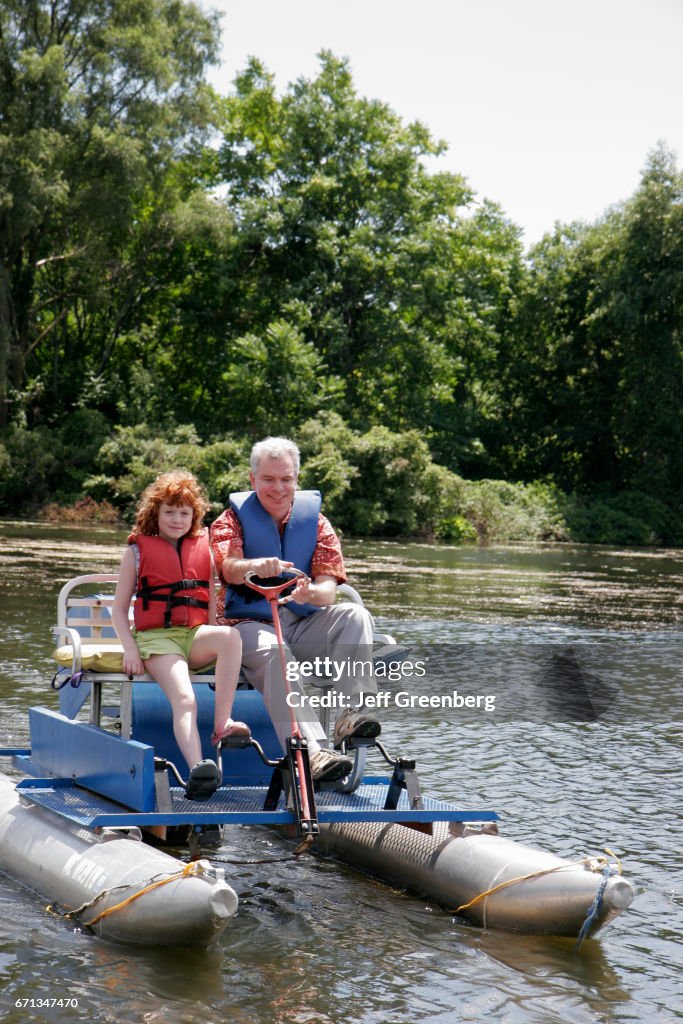 A grandfather and granddaughter on a pontoon paddleboat on Huron River.