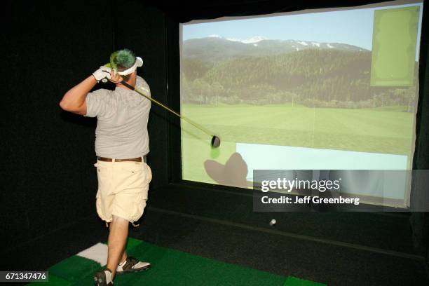 Man taking a swing on a golf simulator at Creekside Golf Course and Training Center.