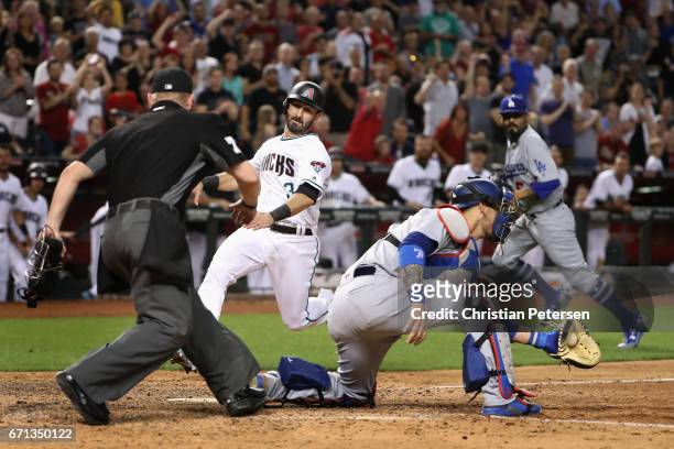 Daniel Descalso of the Arizona Diamondbacks slides in to score a run past catcher Yasmani Grandal of the Los Angeles Dodgers during the eighth inning...