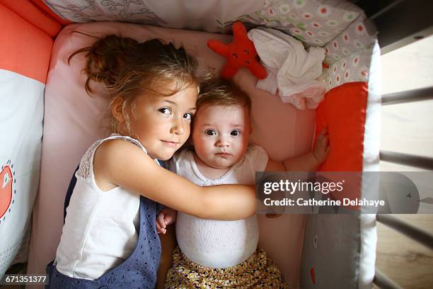 a girl taking care of her baby sister - baby sibling stock pictures, royalty-free photos & images