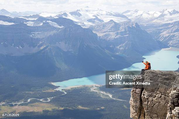 female mountaineer pauses on ridge, takes pic - women rock climbing stock pictures, royalty-free photos & images