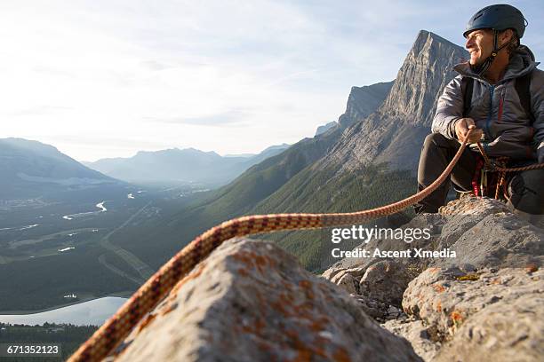 climber looks off to mtns while belaying partner - zekeren stockfoto's en -beelden