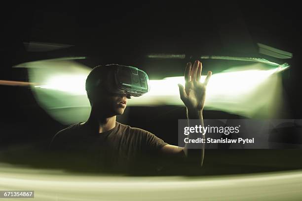 man using vr goggles, touching light - virtualitytrend stockfoto's en -beelden