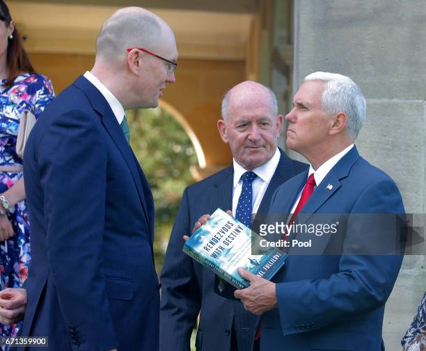 Vice President Mike Pence receives the gift of a book called Rendezvous with Desstiny from author Michael Fullilove alongside Australian Governor...