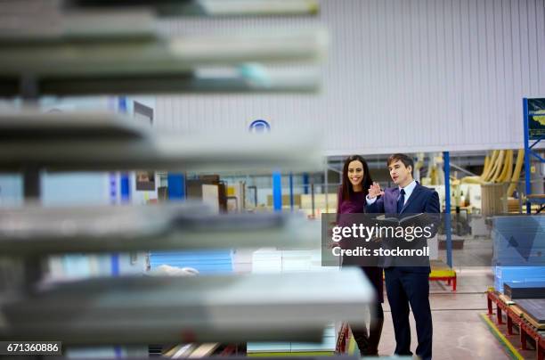 manager discussing with female colleague in a warehouse - business audit stockfoto's en -beelden