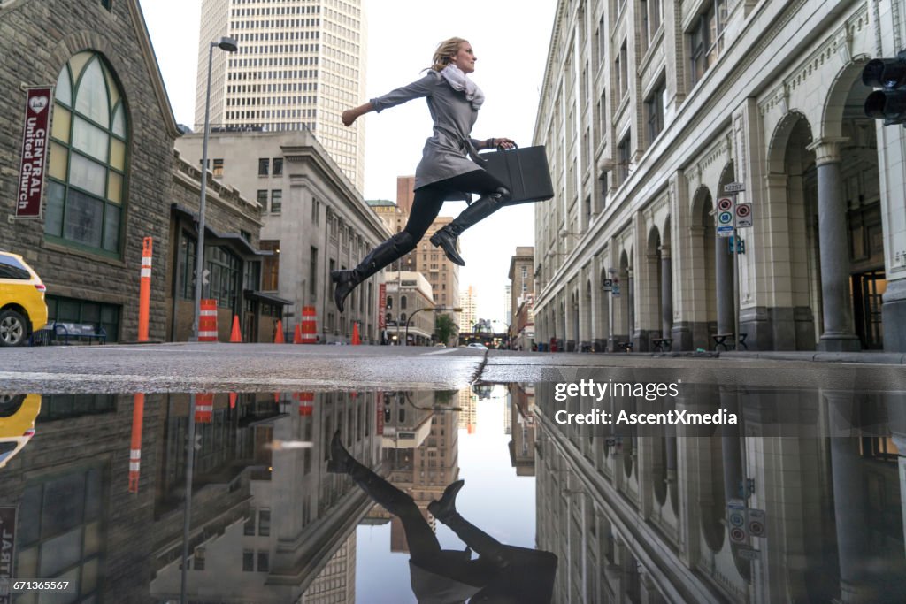 Business woman crosses city street after rain