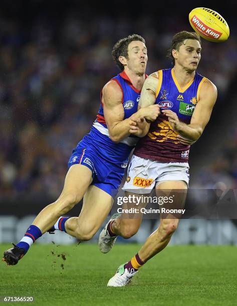 Liam Dawson of the Lions handballs whilst being tackled by Robert Murphy of the Bulldogs during the round five AFL match between the Western Bulldogs...