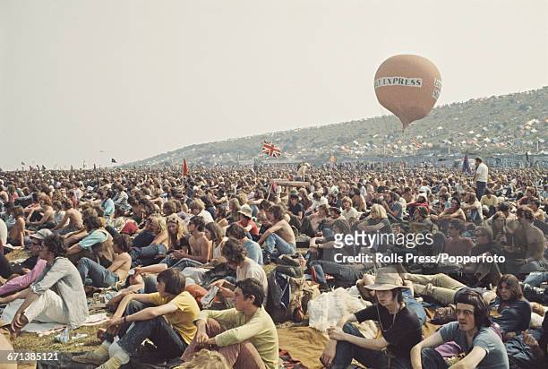 View of hippies and members of the audience pictured sitting on the grass waiting for bands to play on the stage at the Isle of Wight Festival 1970...