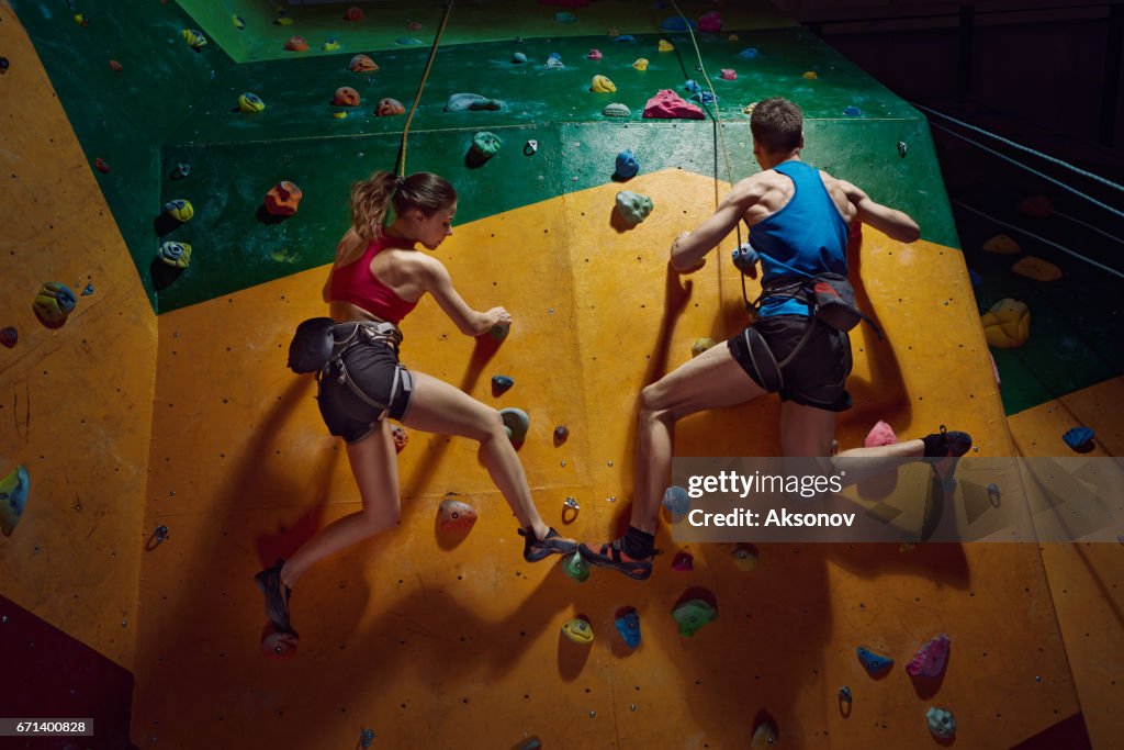 意図的な男性と女性の登山者が登って屋内上昇の壁