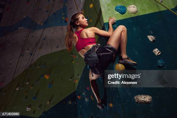 vrouwelijke klimmer doelgericht klimt de indoor klimwand - boulderen stockfoto's en -beelden