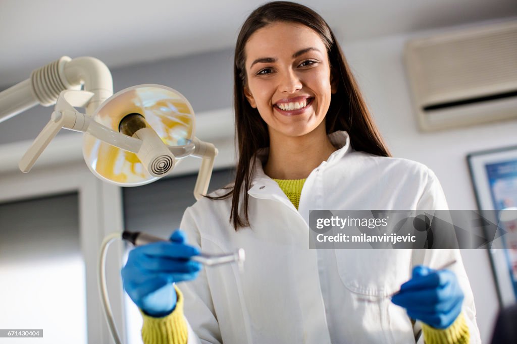 Dentista hermosa con sus herramientas en las manos sonriendo