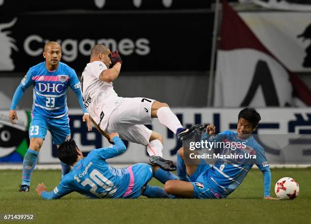 Nilton of Vissel Kobe is tackled by Yoshizumi Ogawa and Akito Fukuta of Sagan Tosu during the J.League J1 match between Sagan Tosu and Vissel Kobe at...
