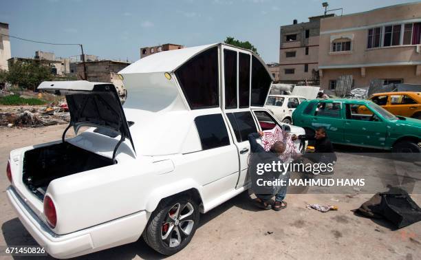 Palestinian mechanic works on his "Cinderella" vehicle at his workshop in Gaza City on April 22, 2017. Made up of five different cars, it will be...