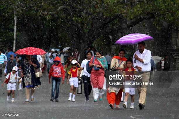 People walking with umbrellas during the rainfall at Ridge, on April 22, 2017 in Shimla, India. The minimum temperature of Shimla was 15.6 degrees...