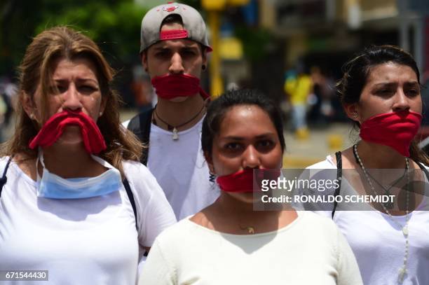 Gagged with red clothes, opposition activists march towards the Catholic Church's episcopal seats nationwide, in Caracas, on April 22, 2017....