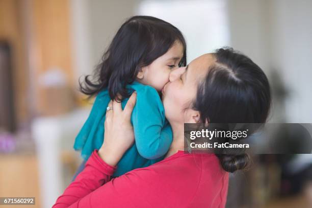 native american mom picks up her young daughter to give her a big kiss - native american family stock pictures, royalty-free photos & images