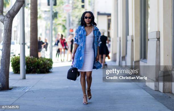 Sonaya wearing a denim jacket, white dress, Prada bag, sandals on April 21, 2017 in Los Angeles, California.