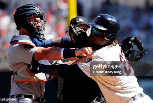 Miguel Sano of the Minnesota Twins and James McCann of the Detroit Tigers clash with home plate umpire Jordan Baker attempting to break up the...