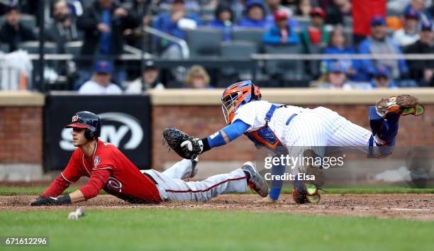 Trea Turner of the Washington Nationals slides home safely in the fifth inning as Rene Rivera of the New York Mets is unable to make the tag on April...