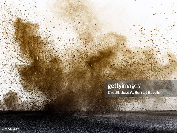 explosion of a cloud of powder of particles of colors gray and brown and a white background - studio shot stock-fotos und bilder