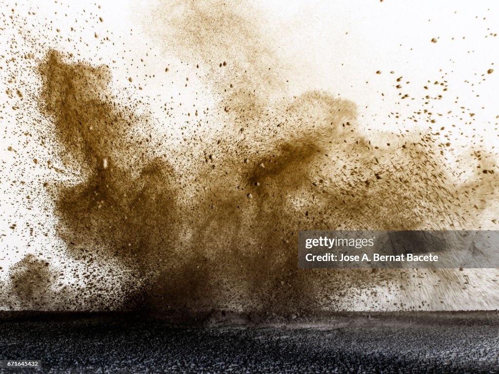 Explosion of a cloud of powder of particles of colors gray and brown and a white background