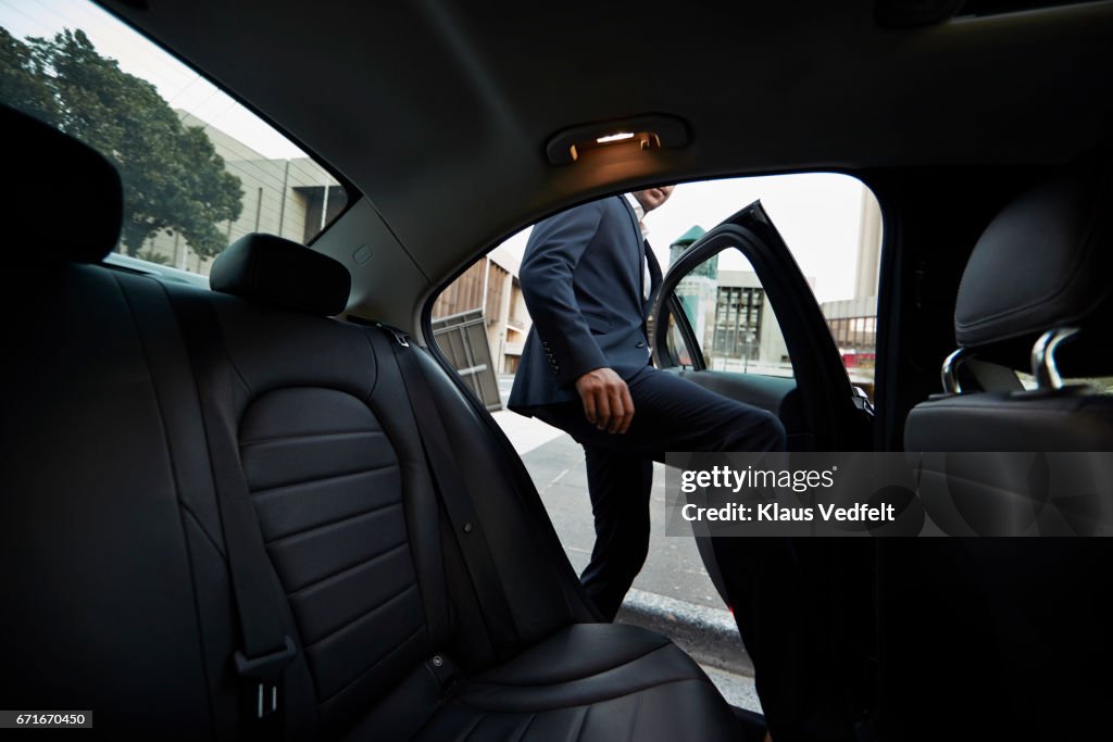 Businessman getting into backseat of exclusive cab