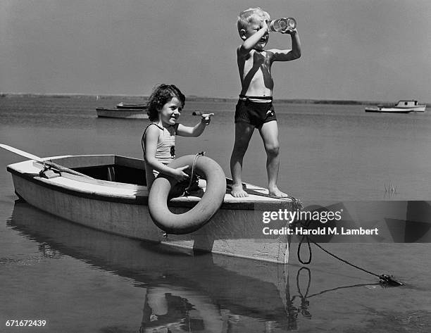 Girl Pointing And Boy Looking Towards Through Binoculars While Playing On Motor Boat.