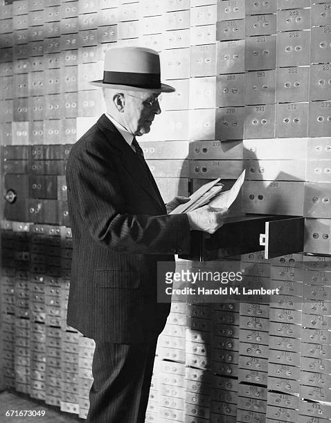 Senior Man Reading Documents In Safety Box Deposit Room.