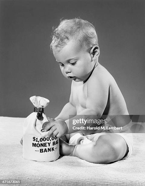 Baby boy examining a money bag.