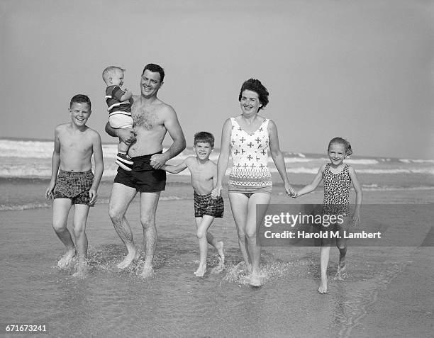 Family of six walk together at the beach.