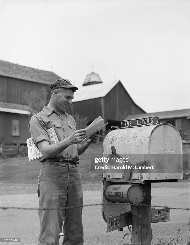 Man Standing Beside Mailbox And Looking Letters
