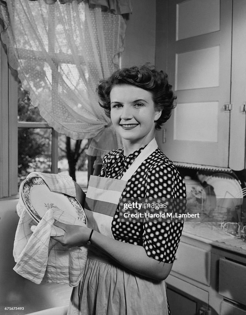   Portrait Of Woman Cleaning Plates And Smiling 