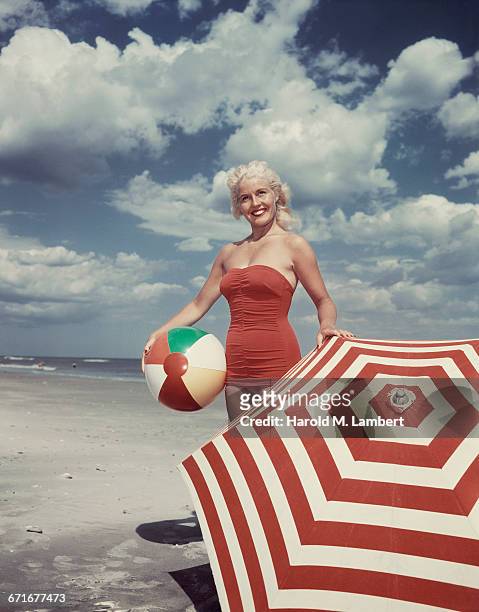 Young Woman Holding Beach Ball Wearing Swimsuit .