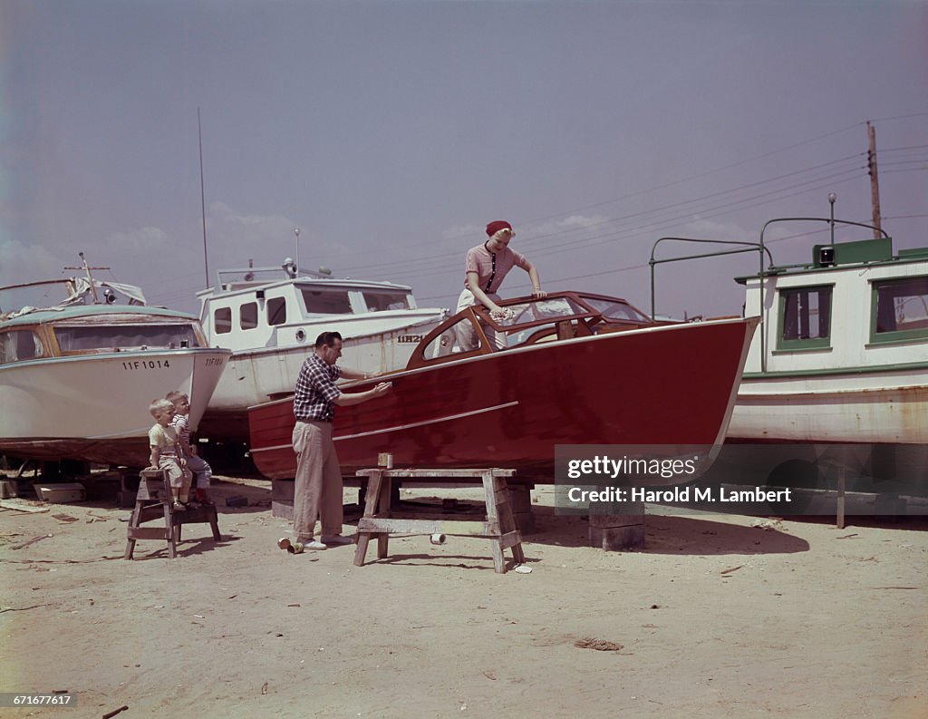 Man And Woman Cleaning Their Boat While Children Looking Them 