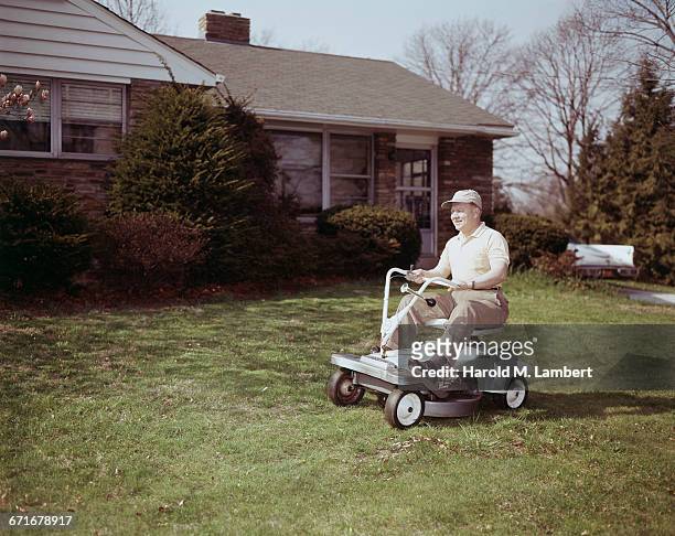 Man Riding Lawn Mower In Backyard .