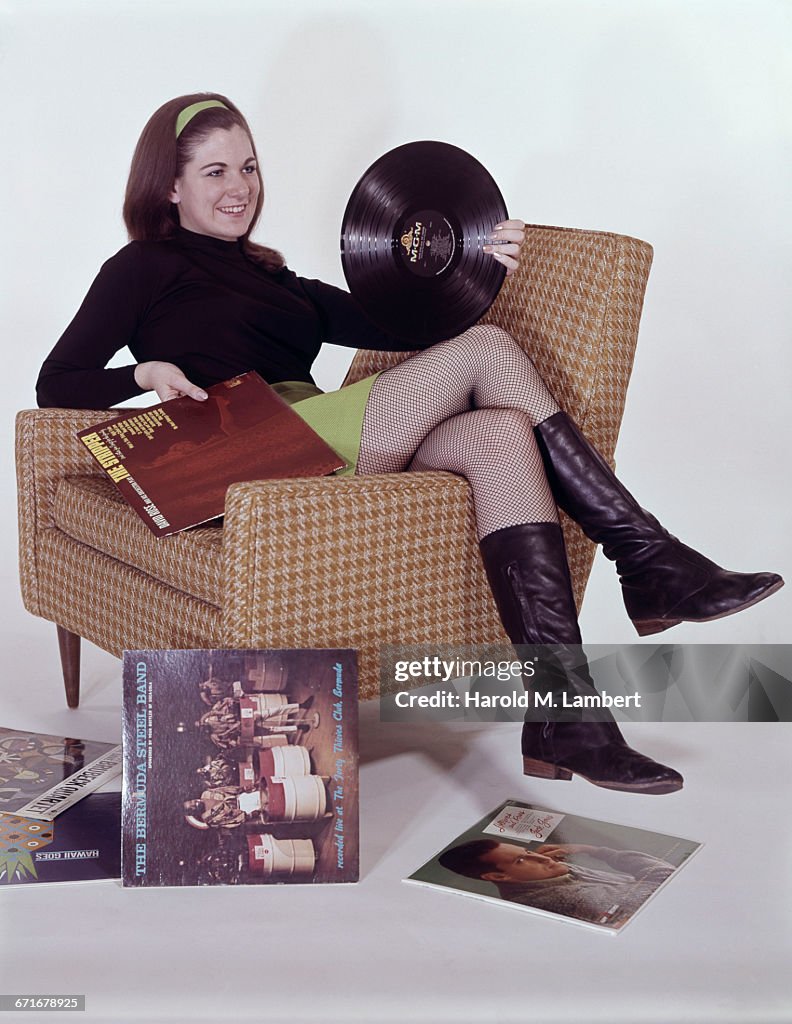 Cheerful Young Woman Holding Disc And Cover While Sitting On Arm Chair 