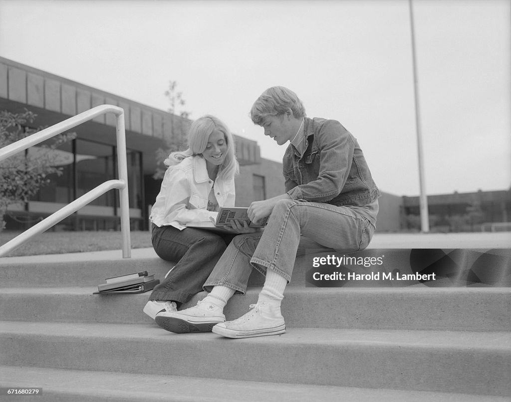  University Students Sitting On Campus Steps And Reading Book