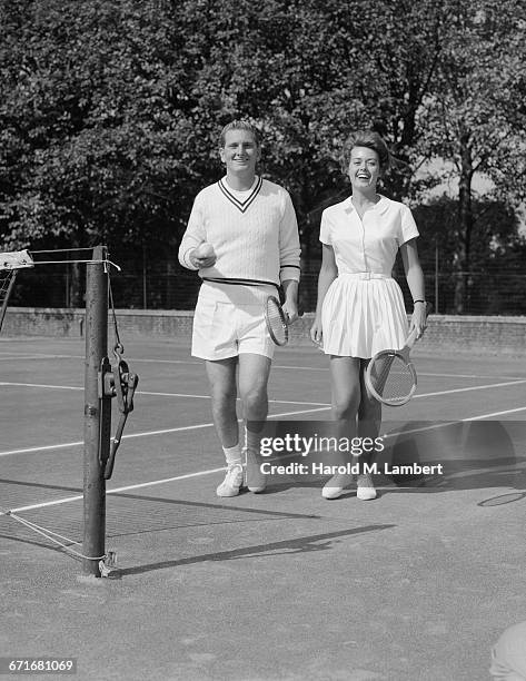 Couple Walking And Holding Tennis Racket And Tennis Ball.