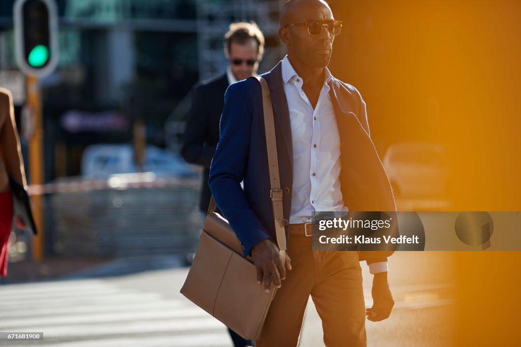 Businesspeople walking in pedestrian crossing with phones and bags