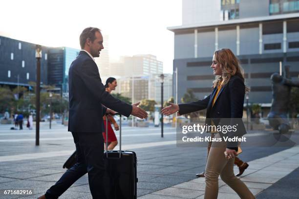 businesspeople meeting up on big square and shaking hands - four people and meeting stock pictures, royalty-free photos & images