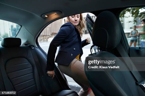 businesswoman getting into cab - betreden stockfoto's en -beelden