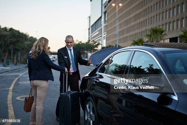 driver assisting businesswoman into cab - luggage trunk stock-fotos und bilder