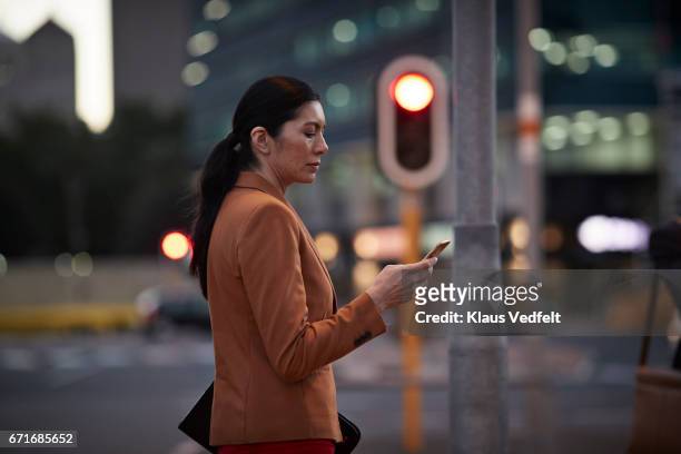 businesswoman on street looking at phone - cape town night stock pictures, royalty-free photos & images
