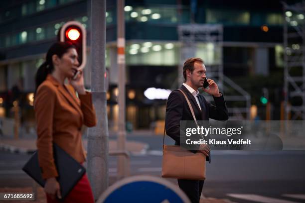 businesspeople on street talking on their phones - semáforo vermelho imagens e fotografias de stock