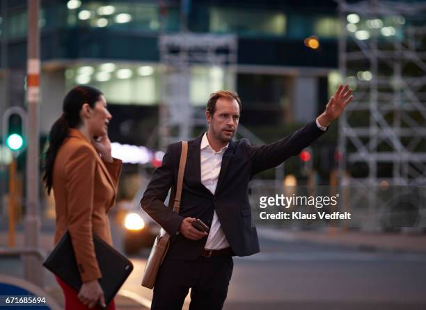 businessman on street hailing cab, at night - calling a cab stock-fotos und bilder