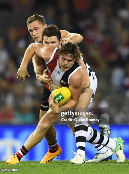 Jack Steven of the Saints handballs whilst being tackled by Patrick Dangerfield and Joel Selwood of the Cats during the round five AFL match between...