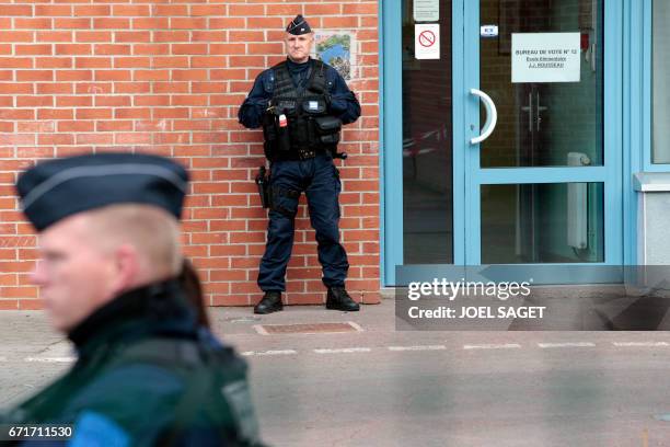 French policemen stand guard outside a polling station in Henin-Beaumont, northern France, on April 23 during the first round of the Presidential...